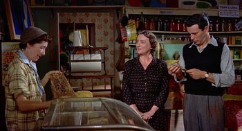 Movie still from “The Trouble with Harry” (1955), directed by Alfred Hitchcock – An older woman standing next to a glass case; Medium shot, Over the shoulder angle