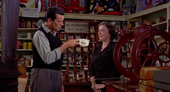 Movie still from “The Trouble with Harry” (1955), directed by Alfred Hitchcock – A man and a woman are talking in a store; Medium shot, Over the shoulder angle