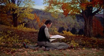 Movie still from “The Trouble with Harry” (1955), directed by Alfred Hitchcock – A man sitting on the ground in the grass; Wide shot, High angle