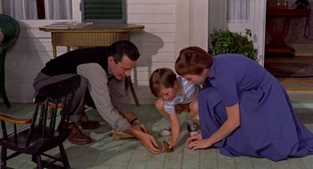 Movie still from “The Trouble with Harry” (1955), directed by Alfred Hitchcock – A man , woman , and child are playing with a toy; Wide shot, High angle
