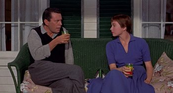 Movie still from “The Trouble with Harry” (1955), directed by Alfred Hitchcock – A man and a woman sitting next to each other holding drinks; Medium shot, Low angle