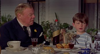 Movie still from “The Trouble with Harry” (1955), directed by Alfred Hitchcock – Two people sitting at a dinner table with food and drinks; Medium shot, Over the shoulder angle