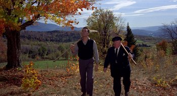 Movie still from “The Trouble with Harry” (1955), directed by Alfred Hitchcock – Two men in suits and hats are standing in a field holding bats; Wide shot, High angle