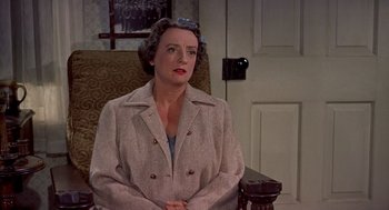 Movie still from “The Trouble with Harry” (1955), directed by Alfred Hitchcock – An older woman sitting in a chair in a room; Medium shot, High angle