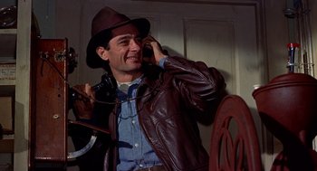 Movie still from “The Trouble with Harry” (1955), directed by Alfred Hitchcock – A man wearing a brown leather jacket and a brown hat; Medium shot, Low angle