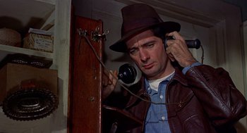 Movie still from “The Trouble with Harry” (1955), directed by Alfred Hitchcock – A man wearing a hat is talking on a phone; Close Up shot, Low angle