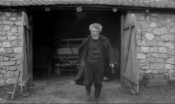 Movie still from “The Turin Horse” (2011), directed by Ágnes Hranitzky – An old man walking through a barn door; Wide shot, Low angle