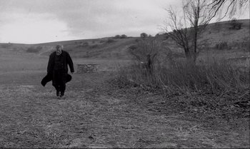 Movie still from “The Turin Horse” (2011), directed by Ágnes Hranitzky – An old man walking on a dirt path; Wide shot, Low angle