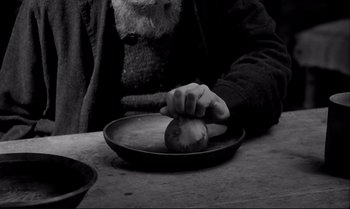 Movie still from “The Turin Horse” (2011), directed by Ágnes Hranitzky – An old man is peeling an apple on a plate; Extreme Close Up shot, Overhead angle