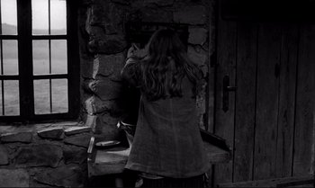 Movie still from “The Turin Horse” (2011), directed by Ágnes Hranitzky – A woman standing in front of a stone wall; Medium shot, Low angle