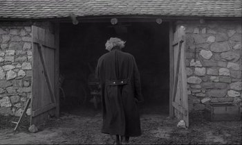 Movie still from “The Turin Horse” (2011), directed by Ágnes Hranitzky – An old man wearing a long black coat; Wide shot, Low angle