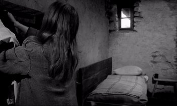 Movie still from “The Turin Horse” (2011), directed by Ágnes Hranitzky – A woman standing next to a bed in a room; Medium shot, High angle