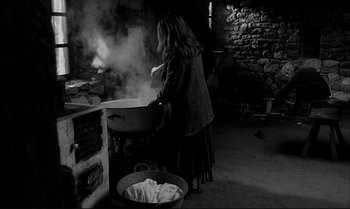 Movie still from “The Turin Horse” (2011), directed by Ágnes Hranitzky – A woman is cooking food in a large pot; Wide shot, High angle