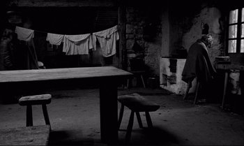 Movie still from “The Turin Horse” (2011), directed by Ágnes Hranitzky – A black - and - white photo of a table and chairs in a room; Wide shot, High angle
