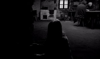 Movie still from “The Turin Horse” (2011), directed by Ágnes Hranitzky – A person sitting in a room with a fireplace; Wide shot, Over the shoulder angle