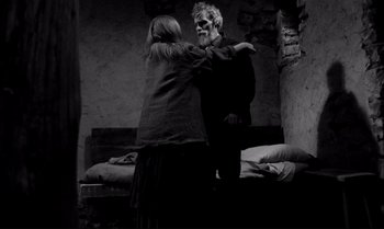 Movie still from “The Turin Horse” (2011), directed by Ágnes Hranitzky – An old man and a young woman are standing in a room; Medium shot, Over the shoulder angle