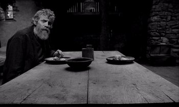 A man sitting at a wooden table with two plates of food