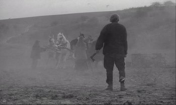 Movie still from “The Turin Horse” (2011), directed by Ágnes Hranitzky – A group of people standing in the dirt; Wide shot, Over the shoulder angle