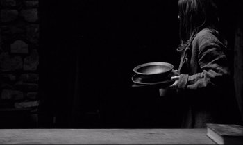 Movie still from “The Turin Horse” (2011), directed by Ágnes Hranitzky – A person holding a pan in one hand and a spoon in the other hand; Medium shot, Low angle