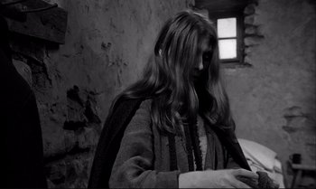 Movie still from “The Turin Horse” (2011), directed by Ágnes Hranitzky – A woman with long brown hair is looking down at her phone; Medium shot, Over the shoulder angle