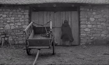 Movie still from “The Turin Horse” (2011), directed by Ágnes Hranitzky – An image of an old fashioned wagon in front of a barn; Wide shot, High angle