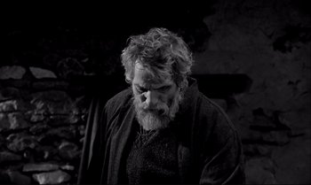 Movie still from “The Turin Horse” (2011), directed by Ágnes Hranitzky – A man with a beard is looking down at the ground; Medium shot, Low angle