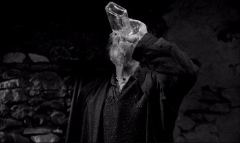 Movie still from “The Turin Horse” (2011), directed by Ágnes Hranitzky – A man with a beard drinking a glass of water; Medium shot, High angle