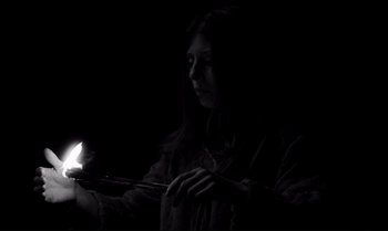 Movie still from “The Turin Horse” (2011), directed by Ágnes Hranitzky – A woman is holding a candle in the dark; Medium shot, Low angle