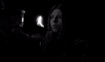 Movie still from “The Turin Horse” (2011), directed by Ágnes Hranitzky – A woman is holding a lit candle in a dark room; Close Up shot, Low angle