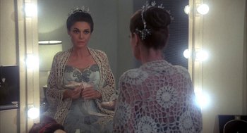 Movie still from “The Turning Point” (1977), directed by Herbert Ross – A woman is looking in the mirror while holding a book; Medium shot, Over the shoulder angle