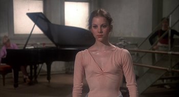 Movie still from “The Turning Point” (1977), directed by Herbert Ross – A woman in a pink shirt standing in front of a piano; Medium shot, Low angle