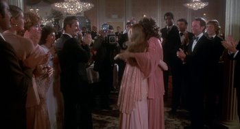 Movie still from “The Turning Point” (1977), directed by Herbert Ross – Two women hugging in a ballroom while people watch; Wide shot, Over the shoulder angle