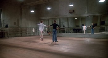 Movie still from “The Turning Point” (1977), directed by Herbert Ross – Two women are holding hands in an empty dance studio; Wide shot, Low angle