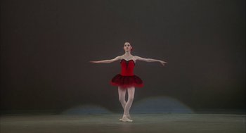 Movie still from “The Turning Point” (1977), directed by Herbert Ross – A woman in a red dress standing on one leg; Wide shot, Low angle