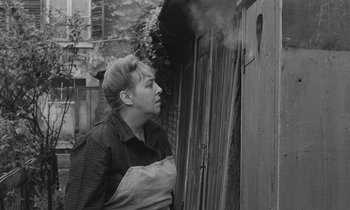 Movie still from “The Two of Us” (1967), directed by Claude Berri – An older woman leaning up against a wooden door; Medium shot, Low angle