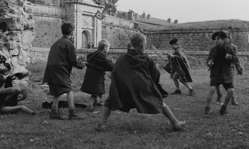 Movie still from “The Two of Us” (1967), directed by Claude Berri – A black and white photo of a group of kids playing tug of war; Wide shot, High angle
