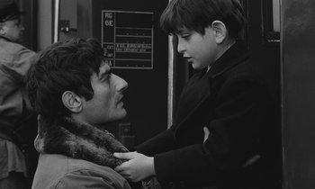 Movie still from “The Two of Us” (1967), directed by Claude Berri – A young boy helping an older man put on a fur collar; Close Up shot, Over the shoulder angle