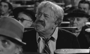 Movie still from “The Two of Us” (1967), directed by Claude Berri – An old man with a beard is sitting at a table; Close Up shot, Low angle