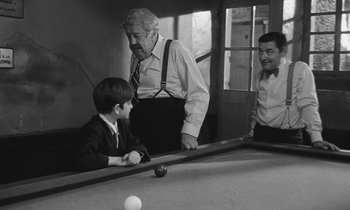 Movie still from “The Two of Us” (1967), directed by Claude Berri – A group of men playing a game of billiards; Medium shot, Over the shoulder angle