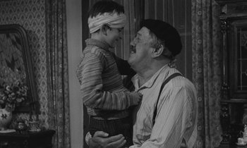 Movie still from “The Two of Us” (1967), directed by Claude Berri – An older man holding a young boy wearing a blindfold; Medium shot, Over the shoulder angle