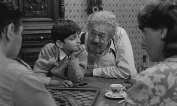 Movie still from “The Two of Us” (1967), directed by Claude Berri – An older man and a young boy sitting at a table; Medium shot, Over the shoulder angle