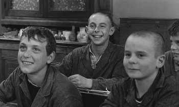 Movie still from “The Two of Us” (1967), directed by Claude Berri – A group of young men sitting next to each other in a room; Medium shot, Over the shoulder angle