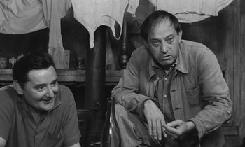Movie still from “The Two of Us” (1967), directed by Claude Berri – A man sitting next to another man on a chair; Medium shot, Over the shoulder angle