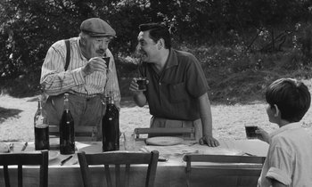 Movie still from “The Two of Us” (1967), directed by Claude Berri – Two men sitting at a picnic table drinking wine; Medium shot, Over the shoulder angle