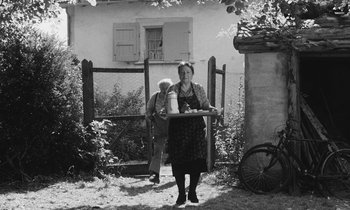 Movie still from “The Two of Us” (1967), directed by Claude Berri – An old photo of a woman and a man standing in front of a gate; Wide shot, Low angle