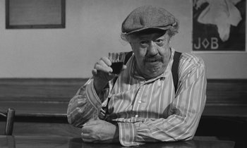Movie still from “The Two of Us” (1967), directed by Claude Berri – An older man holding a glass of wine in his right hand; Close Up shot, High angle