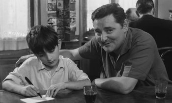 Movie still from “The Two of Us” (1967), directed by Claude Berri – A man and a young boy sitting at a table; Medium shot, Over the shoulder angle