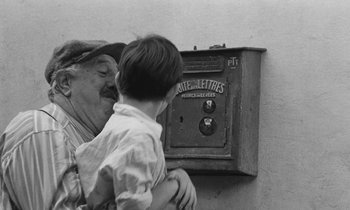 Movie still from “The Two of Us” (1967), directed by Claude Berri – An older man and a young boy in front of an old mail box; Medium shot, Low angle