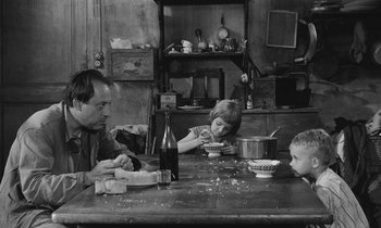 Movie still from “The Two of Us” (1967), directed by Claude Berri – A man and two children sitting at a dinner table; Medium shot, High angle