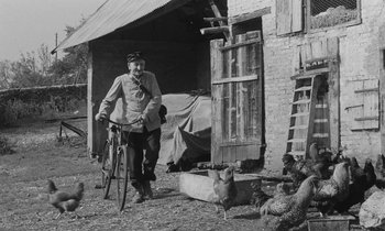 Movie still from “The Two of Us” (1967), directed by Claude Berri – An old man standing next to a bicycle in front of a building; Wide shot, Low angle